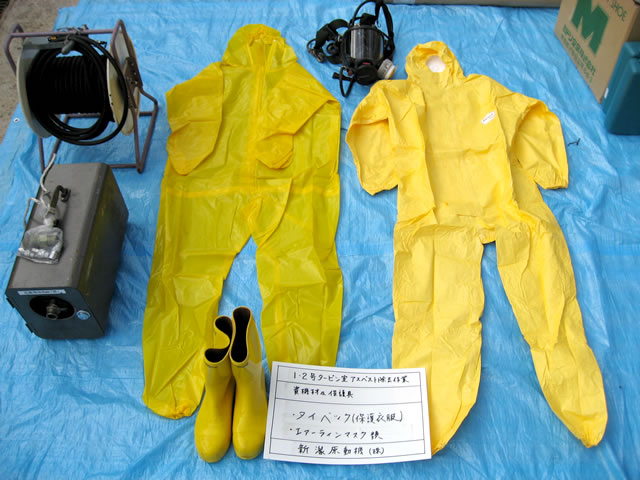 作業時に着る防護服が床に置かれている写真